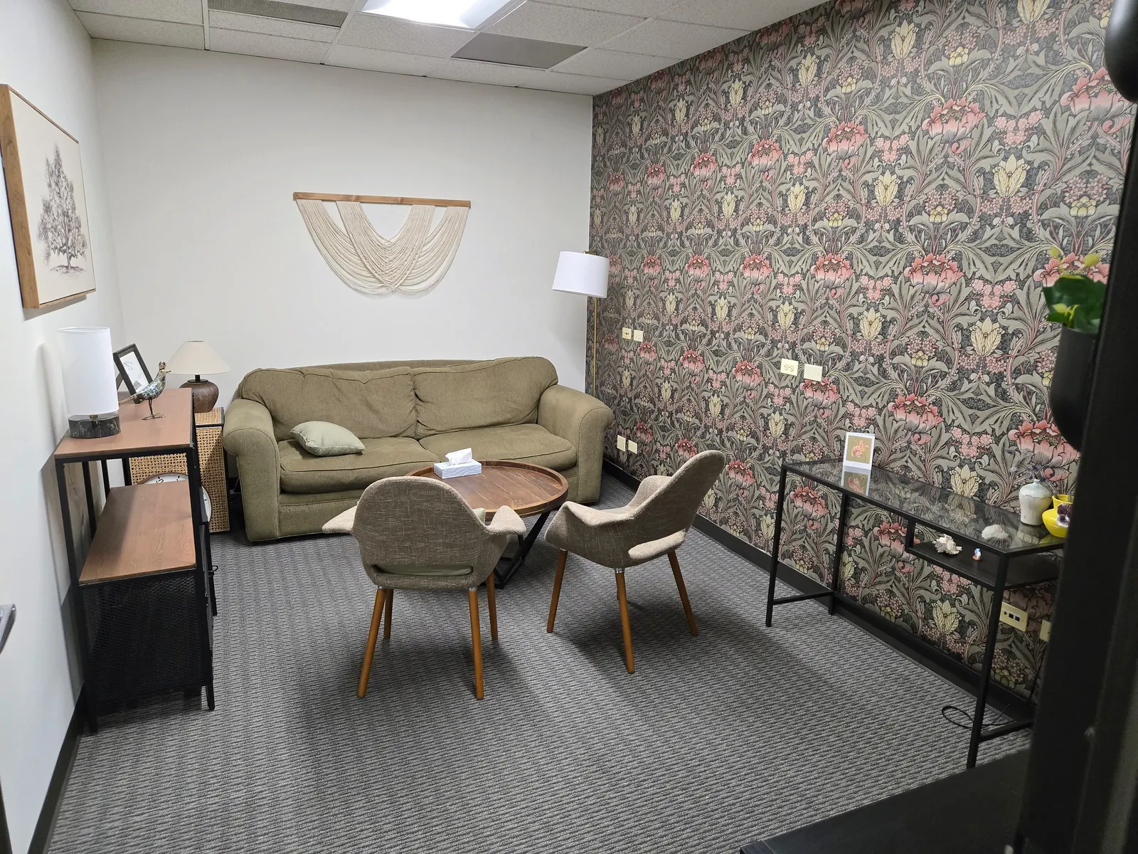 Room 108 with patterned wallpaper, a green sofa, two chairs and a round coffee table